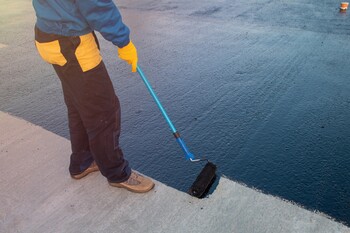 Roofer applying roof coating in China Grove, NC